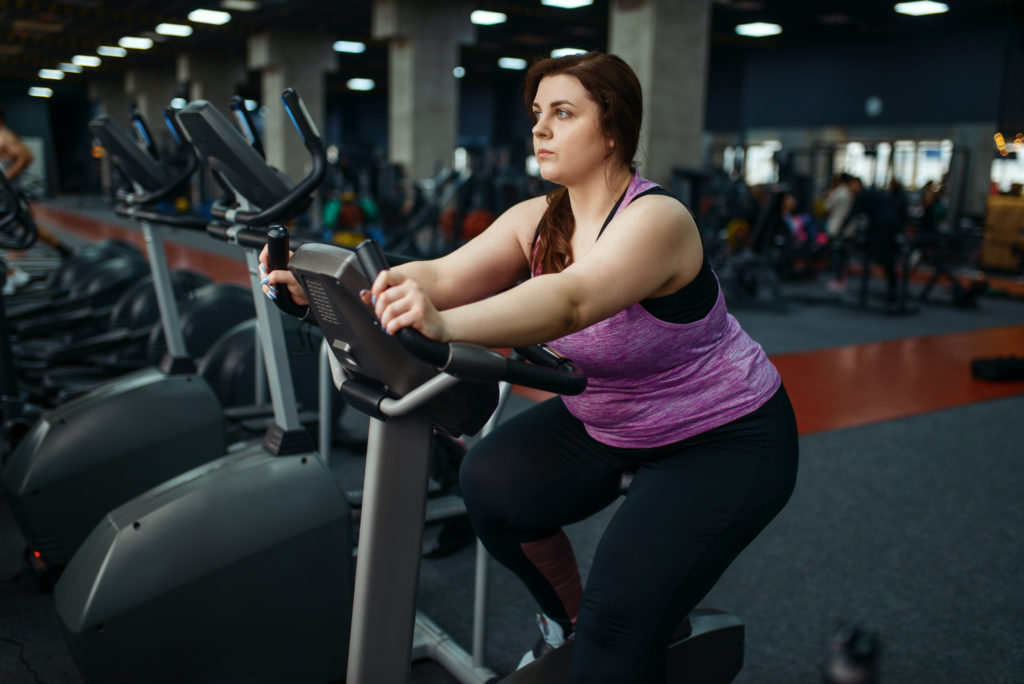 mujer con sobrepeso haciendo ejercicio en la bicicleta estática